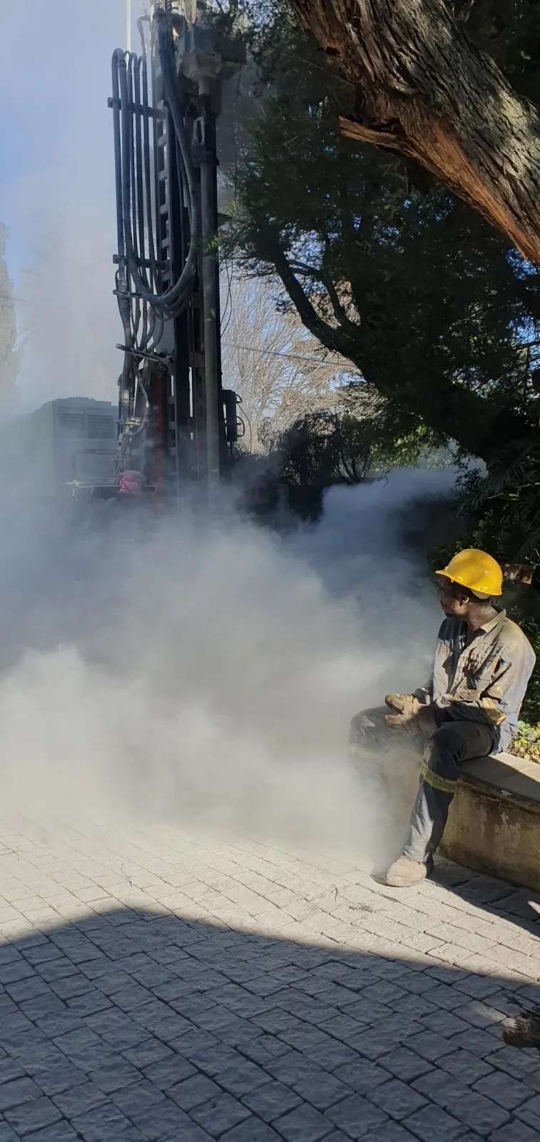 Worker beside active drilling steam cloud – borehole drilling in progress